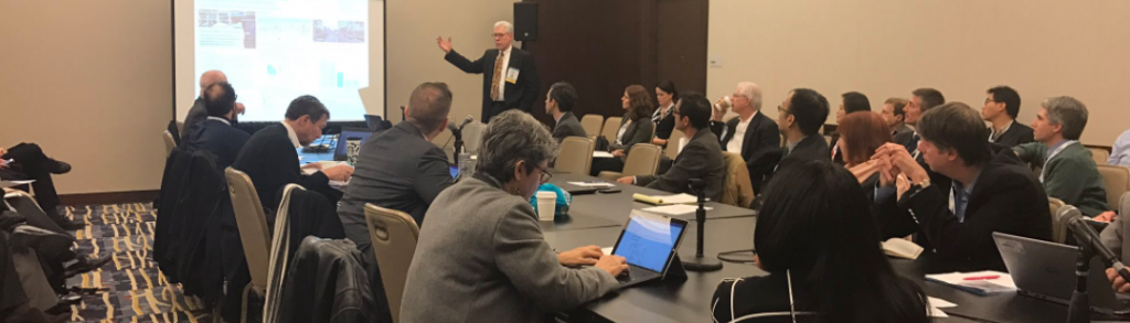 Photo of a man presenting to a committee at an in-person meeting.
